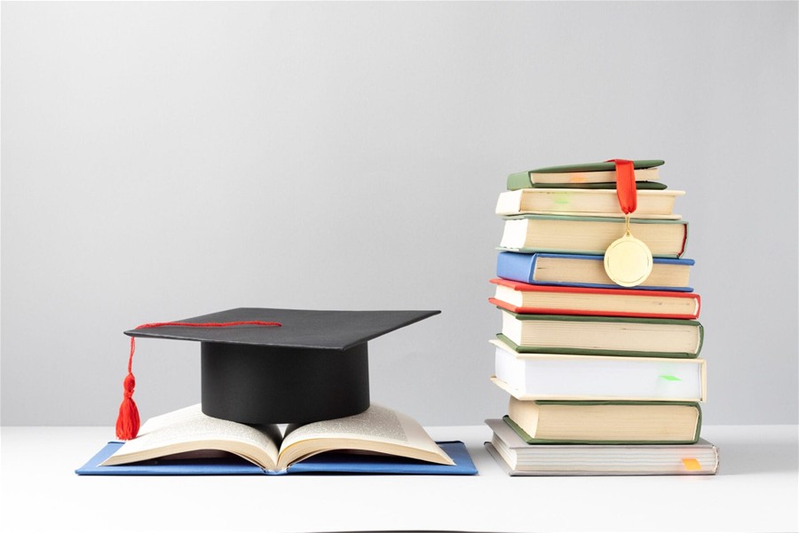 libri di testo con sopra cappello universitario e medaglia